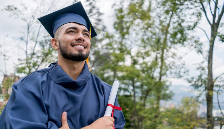 Graduação: homem jovem trajando beca de formatura com seu diploma em mãos