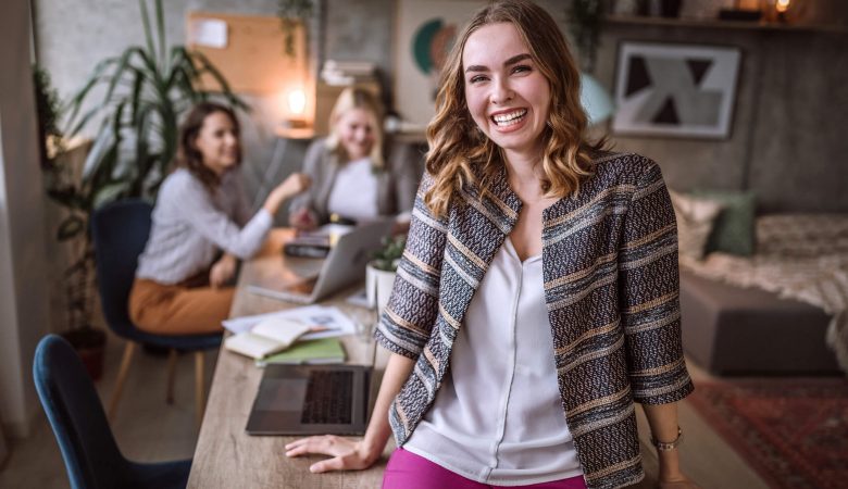 como ser um empreendedor: jovem mulher sorrindo em ambiente de escritório descontraído